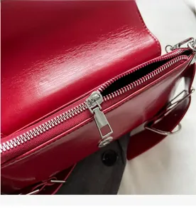 Close-up of smooth silver zipper and premium red leather texture on luxury crossbody bag