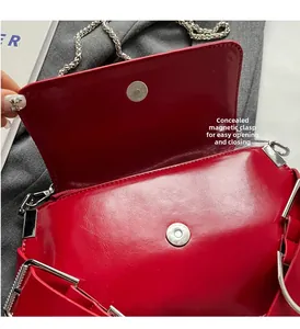 Detail of red glossy leather bag featuring a secure hidden magnetic closure and silver chain