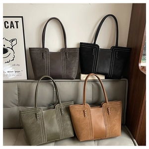 Detalle de bolsos tote de cuero mate vintage en cuatro colores en un sofá gris