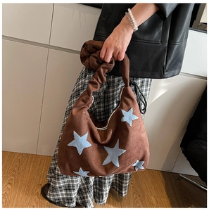 Detail of brown faux suede tote bag featuring light blue plush star embroidery and ruffled handle