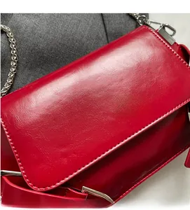 Detail of red glossy faux leather texture with silver chain and metal buckle closure