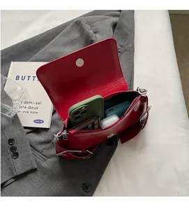 Interior capacity of red leather shoulder bag showing phone, power bank and accessories