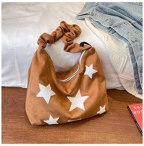 Detail of brown suede tote bag featuring white stars and a ruffled shoulder strap