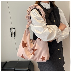 Detail of pink faux suede tote bag featuring a star patch and pleated shoulder strap