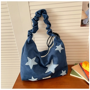 Detail of blue suede shoulder bag featuring embroidered stars and a ruffled strap handle