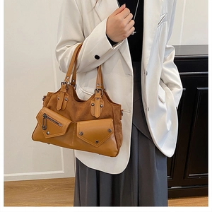 Detail of brown patchwork handbag featuring dual pockets and metallic zipper accents