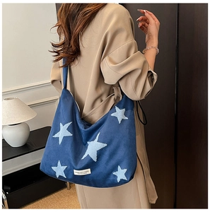 Detail of dark blue suede tote with embroidered light blue stars and brand label