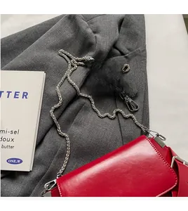 Detail of red crossbody bag with silver metal chain and thin leather shoulder strap