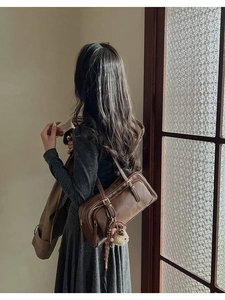 Detail of vintage brown leather underarm bag with cute plush bear pendant accessory