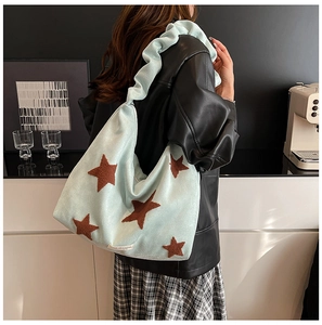 Detail of mint green suede bag featuring star patches and a ruffled shoulder strap