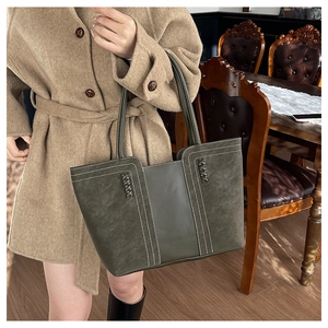 Detalle de bolso tote vintage verde oscuro con costuras en contraste y detalles tejidos