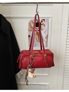 Detail of red faux leather shoulder bag with zipper tassels and plush animal charm decoration