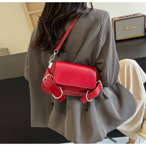 Detail view of red glossy leather crossbody bag with decorative silver buckles