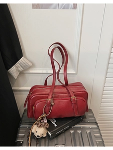 Detail of red faux leather handbag with cute bear charm and golden zipper compartments
