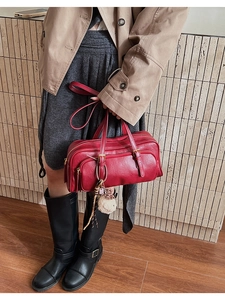 Detail of red leather shoulder bag with multiple zippers and beige plush charm