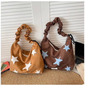 Detail of crescent shoulder bags with star embroidery and trendy ruched straps on a mat