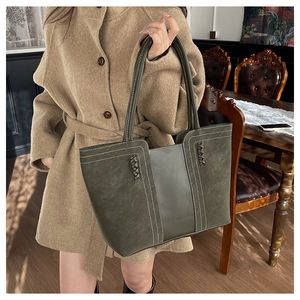 Vista detallada del bolso tote de cuero verde oliva oscuro con costuras blancas en contraste