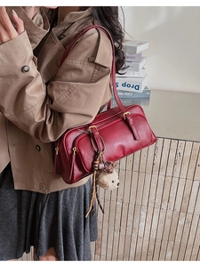 Detail of burgundy faux leather crossbody bag with dual straps and plush bear charm