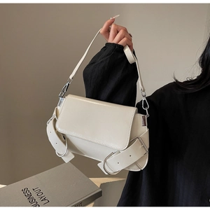 Chic cream leather shoulder bag with wide adjustable buckle strap and fold-over flap design