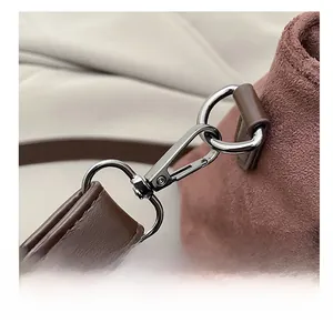 Macro shot of gunmetal hook buckle on brown leather strap with reddish suede fabric