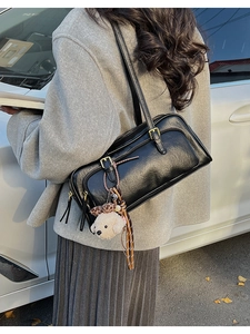 Detail of black pebbled leather handbag with teddy dog and leopard tassel charms