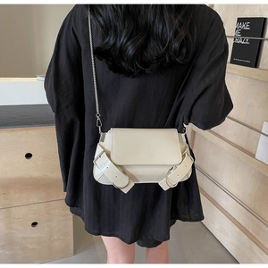 Detail view of cream leather crossbody bag with silver buckles and chain strap