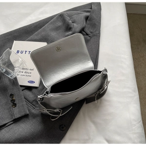Detailed view of silver shoulder bag showing magnetic metal buckle and large ring strap
