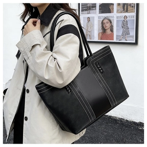 Detalle del bolso tote de cuero negro con costuras blancas en contraste y trenzado
