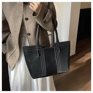 Detalle de bolso tote de cuero PU negro mate con costuras blancas y detalles trenzados