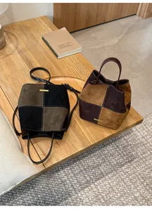 Detail of color-block bucket bags with gold hardware on a rustic wooden bench