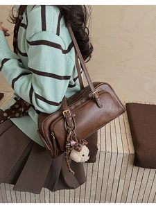 Close-up of brown retro shoulder bag with decorative straps and plush animal charm detail