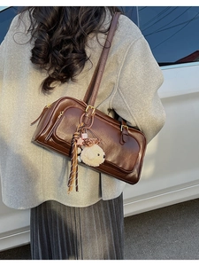 Detail of dark brown leather crossbody bag with tassel and plush animal charm