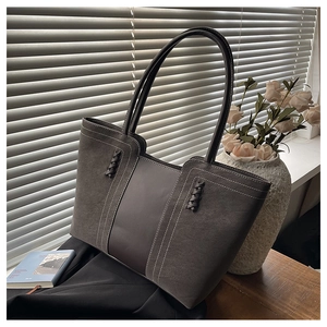 Detalle de bolso tote gris oscuro con costuras en contraste y asa trenzada artesanal