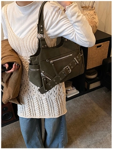 Detail of dark green hobo bag with multi-pocket design and decorative metal eyelets