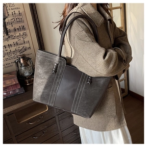 Detalle del bolso tote de ante marrón con costuras en contraste y asa trenzada retro