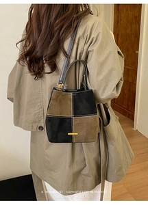 Close-up of retro suede bucket bag with contrast stitching and golden hardware plate