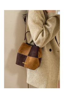 Detailed close-up of two-tone brown frosted leather bucket bag with gold metal logo
