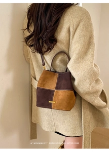 Detail of retro color-block bucket bag with contrast stitching and metal logo
