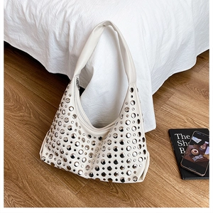 Detail of a beige leather hobo bag featuring polished silver rivet stud embellishments