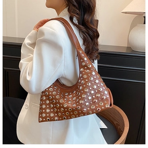 Detail of brown PU leather hobo bag featuring silver rivets and half-moon design on model