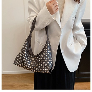 Detailed close-up of a half-moon hobo bag with silver metal rivets and leather strap