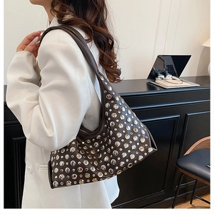 Close-up of trendy brown shoulder bag with silver rivet studs on textured leather strap