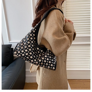 Detail shot of a black hobo shoulder bag with silver studs on a stylish female model