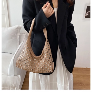 Detail shot of beige hobo bag featuring dense silver metal rivets and elegant finish