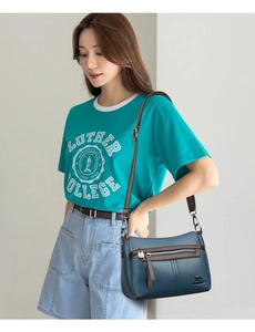 Detail showing dark blue lychee grain leather bag with brown strap and metal logo