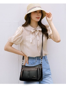 Detail of black pebbled leather crossbody bag with brown trim and kangaroo logo