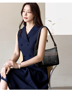 Detail of black lychee grain leather bag with contrast stitching and golden logo