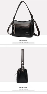 Detail view of black lychee texture crossbody bag with contrast brown strap and logo