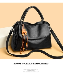 Détail du sac en cuir noir avec pompon en perles de bois et fermeture éclair