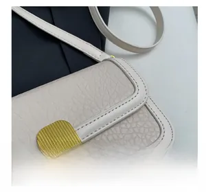 Macro detail of beige pebble leather handbag showing precision stitching and gold buckle